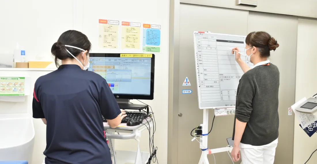 画像:看護師がパソコン/ホワイトボードを使用している