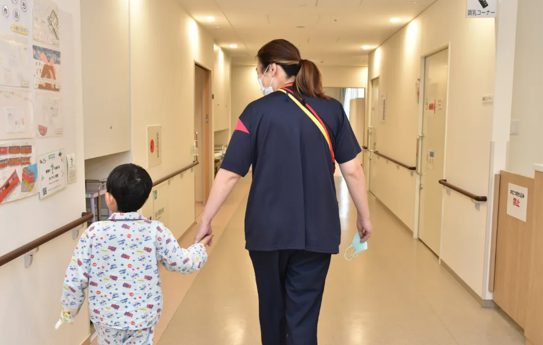 画像:看護師と子どもが手を繋いで歩いている